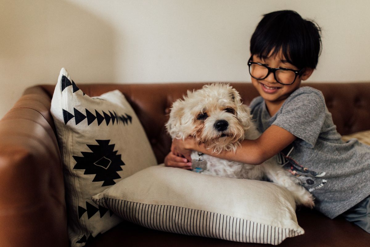 a kid hugging a dog over sofa